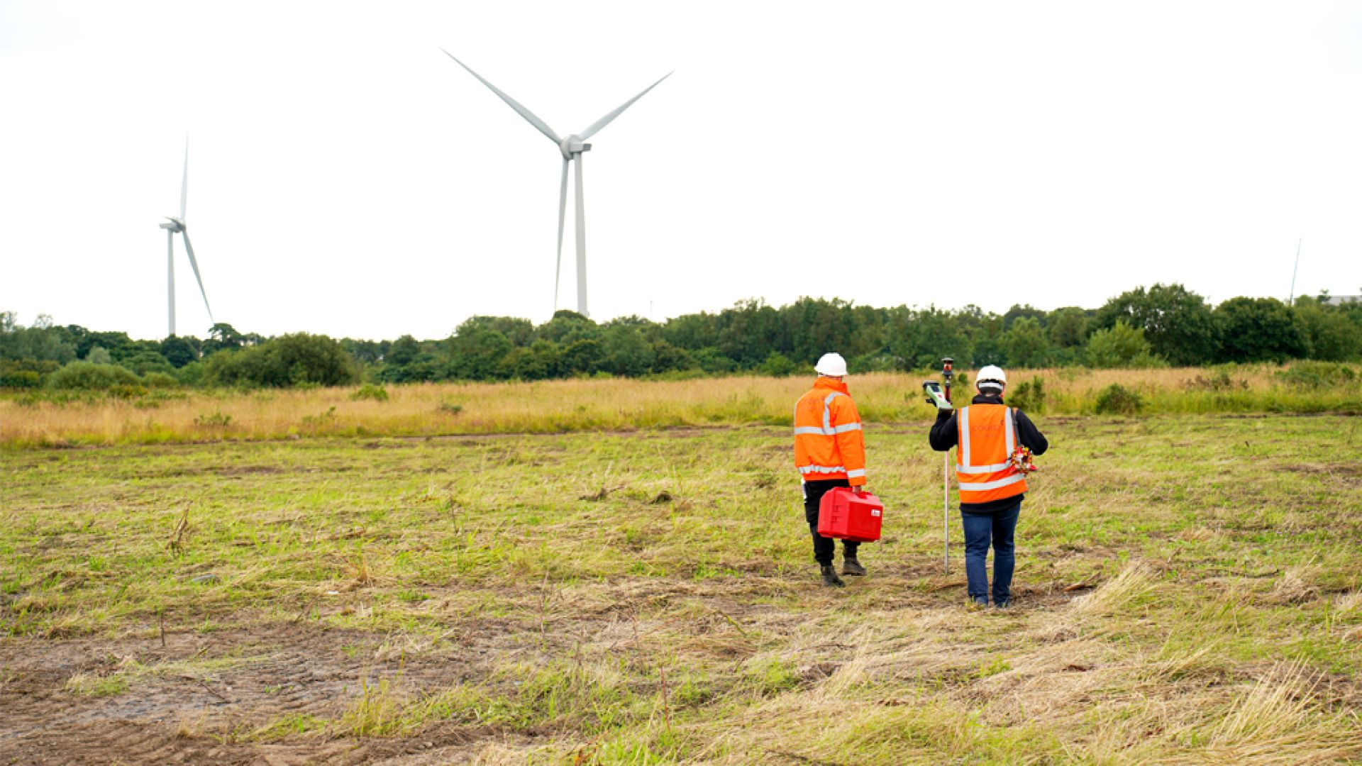 walking through field with turbines in background